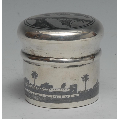 289 - An Iraqi silver and niello cylindrical box and cover, decorated with an Arab Desert scene, 5cm high