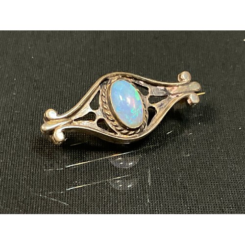 464 - An Arts & Craft oval opal cabochon inset shaped brooch, unmarked silver coloured metal mount, the op... 