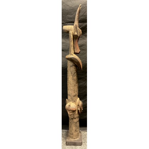 20 - A Nigerian spirit totem, two horned mask top, plain column with triple masked band, painted detailin... 