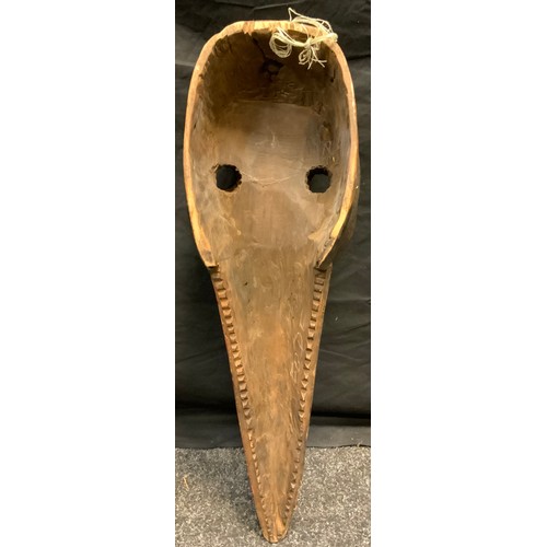 34 - An African tribal zoomorphic dan bird mask, hole eyelets, elongated beak, nailed details, picked out... 