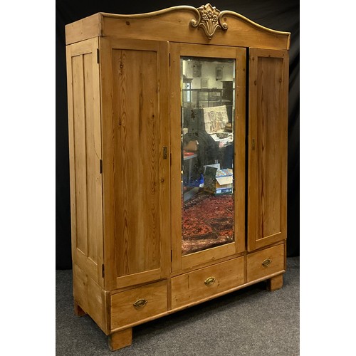 107 - A Victorian pine double wardrobe, serpentine pediment with carved cresting, above a central mirrored... 