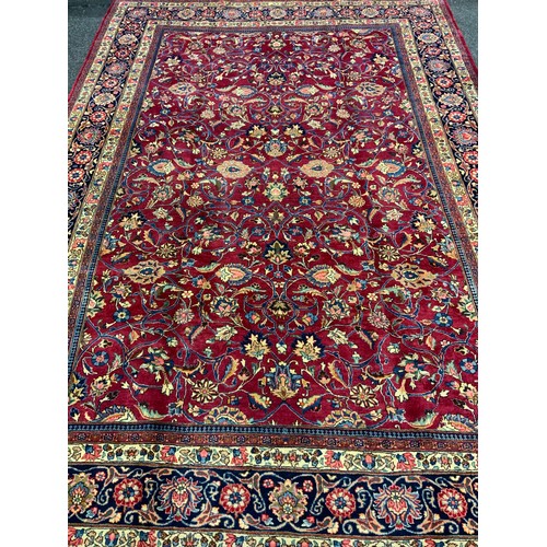 283 - A Persian Tabriz hand-knotted rug / carpet, the field in rich red with scrolling tendrils of stylise... 