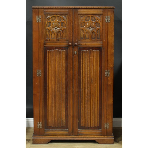 320 - An oak bedroom suite, Gothic Revival style and linenfold elements, comprising wardrobes 185.5cm wide... 