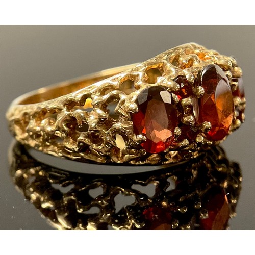 1184 - A 9ct gold and garnet three stone ring, the faceted oval cut stones graduating, fancy shank