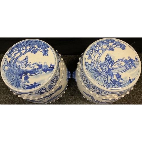 64 - A pair of 20th century Chinese blue and white ceramic barrel stools, decorated with children in land... 