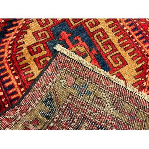 107 - A North West Persian Heriz runner carpet, hand-knotted in rich tones of red, blue, and ochre, with a... 