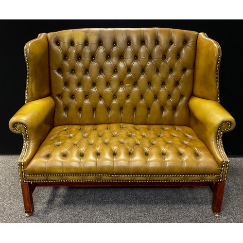 320 - A George III style reproduction Chesterfield wing-back bench sofa, deep button back, pale tan leathe... 