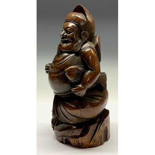 3075 - A Chinese bamboo figure, carved as a rotund Buddhist monk holding a fish, 28cm high