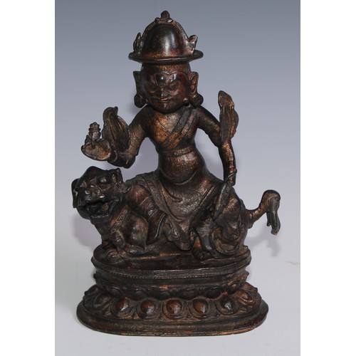 3664 - Tibetan School, a red and gilt patinated bronze, Vajrasadhu seated on a lion, lotus base, 28cm high