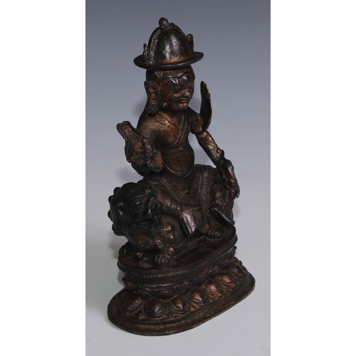 3664 - Tibetan School, a red and gilt patinated bronze, Vajrasadhu seated on a lion, lotus base, 28cm high