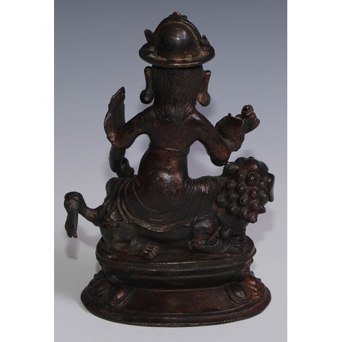 3664 - Tibetan School, a red and gilt patinated bronze, Vajrasadhu seated on a lion, lotus base, 28cm high