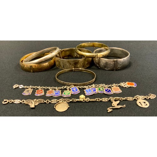 416 - A silver hinge bangles;  others, silver gilt; slide action;  enamelled silver shield charms bracelet... 