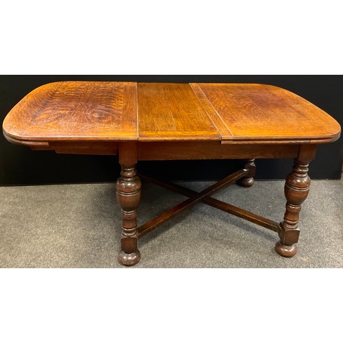 61 - A mid 20th century oak extending dining table, rounded rectangular top, turned legs, X-frame stretch... 