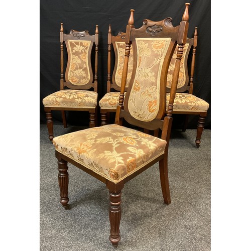 79 - A set of four Art Nouveau walnut dining chairs, turned finials, upholstered shield-shaped backs, and... 