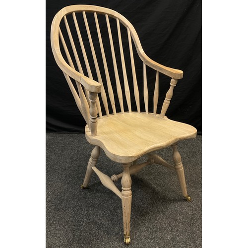 124 - An elm high spindle-back armchair, shaped seat, H-stretcher, turned legs, brass casters, 103cm high ... 