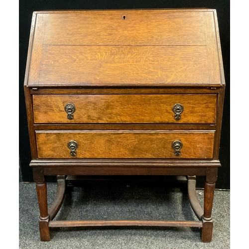 46 - A mid 20th century oak bureau, fall top with fitted interior, above two long drawers, turned support... 