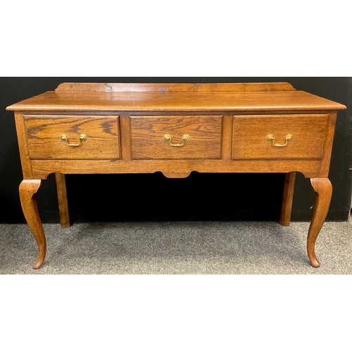 54 - A reproduction Georgian style oak dresser base / sideboard, over-sailing top, three deep drawers to ... 