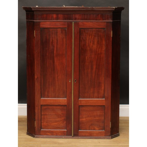 228 - A 19th century mahogany splay front corner cabinet, moulded cornice above a pair of panel doors, enc... 