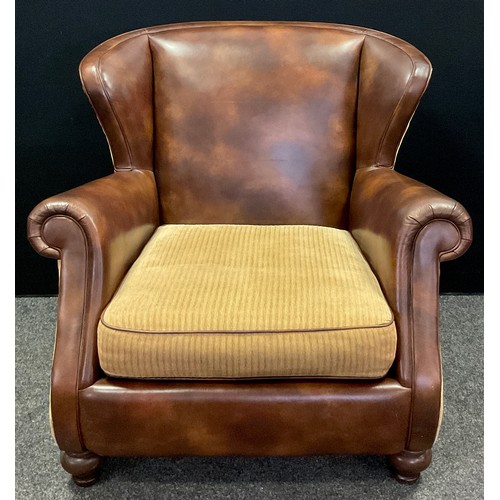 25 - A contemporary tan leather and fabric wingback armchair, scroll arms, turned feet, 92cm high x 99cm ... 