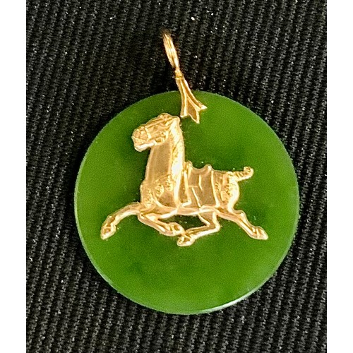 457 - A circular jade and gold coloured metal pendant, set to centre with a horse