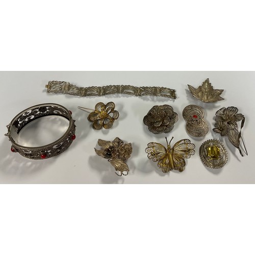 511 - A silver filigree bangle, assorted silver filigree brooches, butterfly, flowers, etc; a similar brac... 