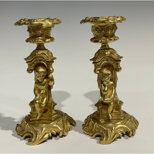 2082 - A pair of French Rococo style gilt bronze candlesticks, each stem with seated putti within sculpture... 