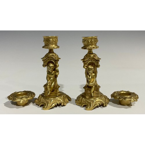 2082 - A pair of French Rococo style gilt bronze candlesticks, each stem with seated putti within sculpture... 