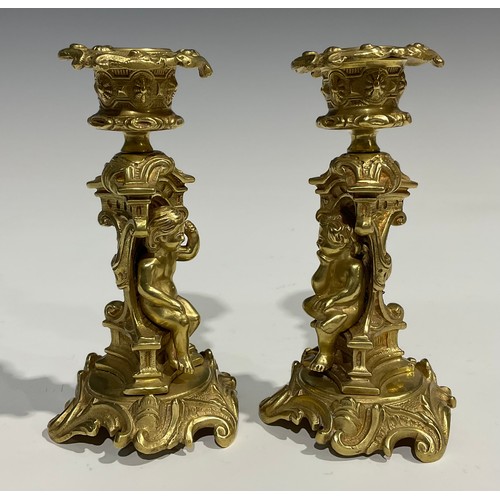 2082 - A pair of French Rococo style gilt bronze candlesticks, each stem with seated putti within sculpture... 