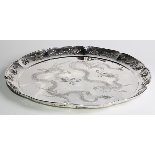 989 - A large Chinese silver shaped circular serving tray, the field engraved with a pair of dragons, the ... 