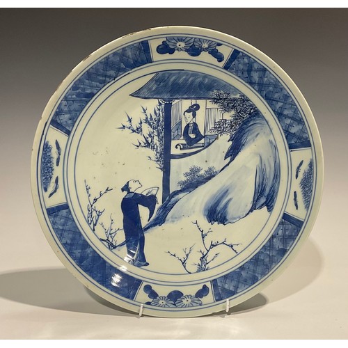 481 - An 18th century Chinese charger, decorated in underglaze blue with gentleman serenading a lady at a ... 