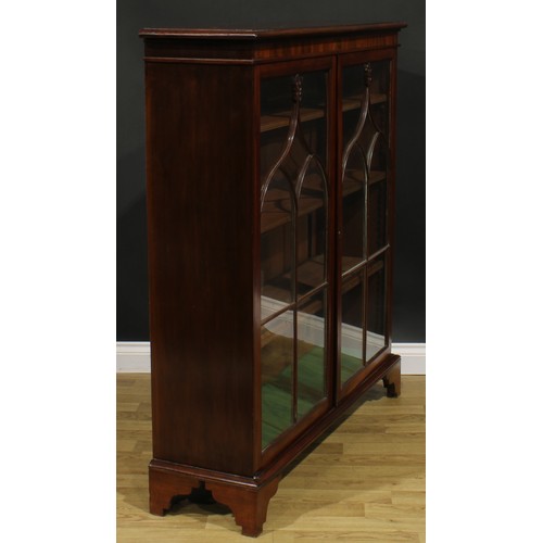 1634 - A 19th century mahogany low library bookcase, oversailing top above a pair of glazed doors enclosing... 