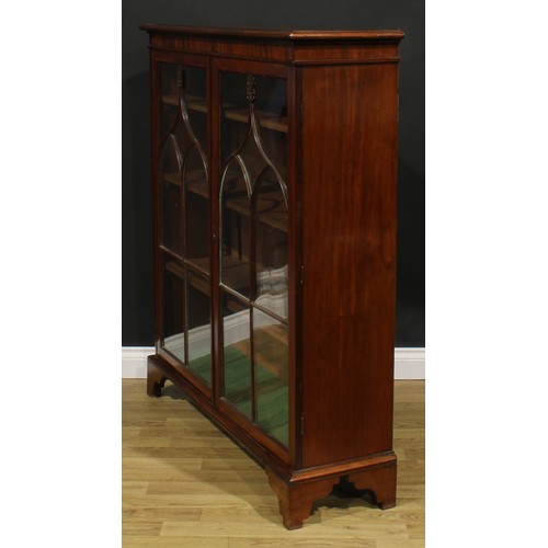 1634 - A 19th century mahogany low library bookcase, oversailing top above a pair of glazed doors enclosing... 