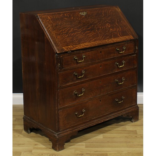 1940 - A George III oak bureau, fall front enclosing a small door, small drawers and pigeonholes, above fou... 