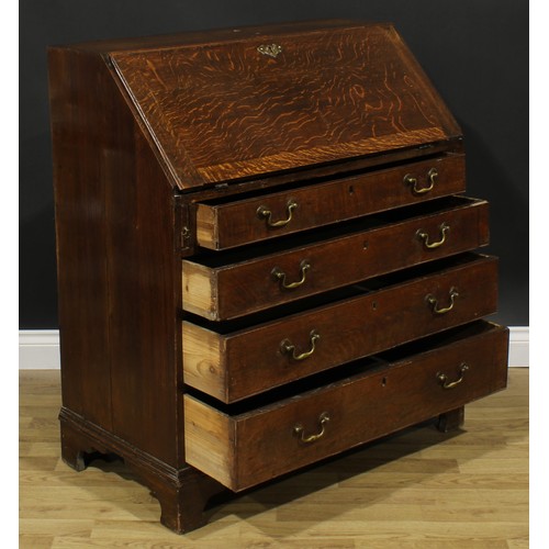 1940 - A George III oak bureau, fall front enclosing a small door, small drawers and pigeonholes, above fou... 