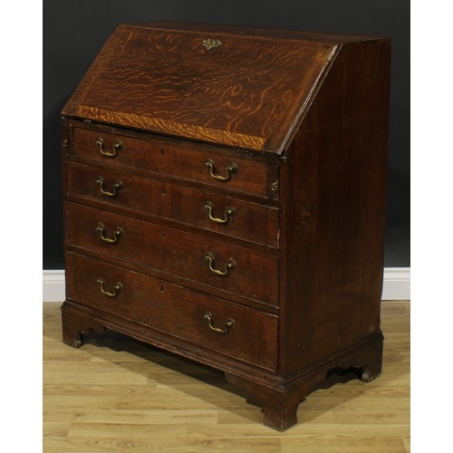 1940 - A George III oak bureau, fall front enclosing a small door, small drawers and pigeonholes, above fou... 