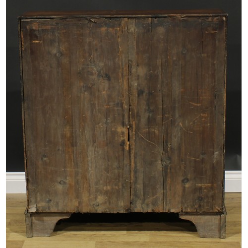 1940 - A George III oak bureau, fall front enclosing a small door, small drawers and pigeonholes, above fou... 