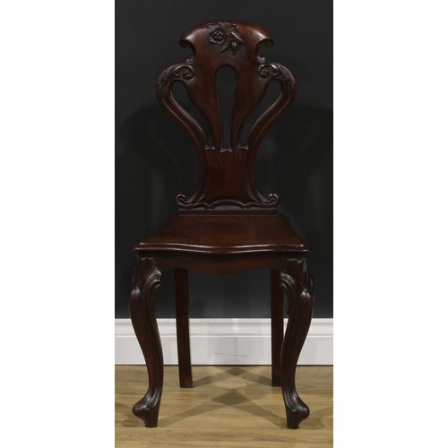 2535 - A pair of Victorian mahogany hall chairs, each with a pierced cartouche shaped back carved with a fl... 