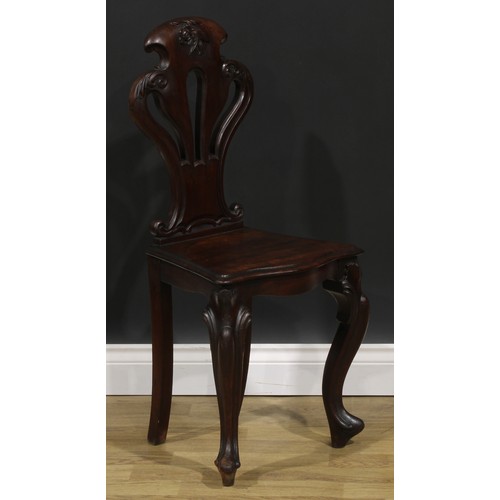 2535 - A pair of Victorian mahogany hall chairs, each with a pierced cartouche shaped back carved with a fl... 