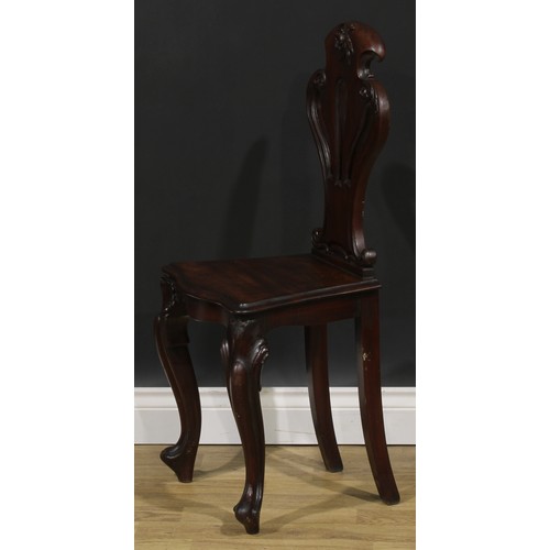 2535 - A pair of Victorian mahogany hall chairs, each with a pierced cartouche shaped back carved with a fl... 