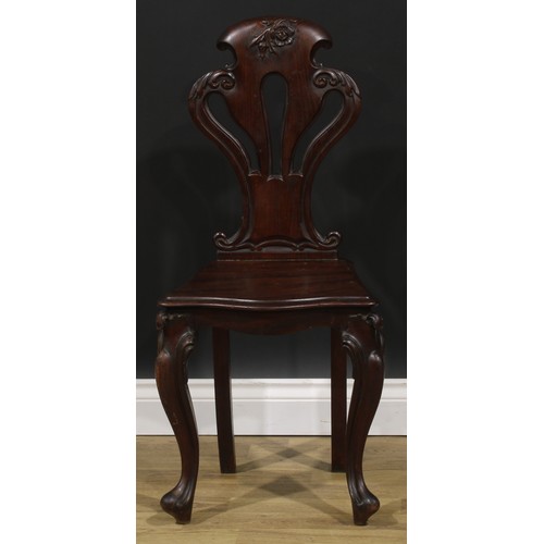 2535 - A pair of Victorian mahogany hall chairs, each with a pierced cartouche shaped back carved with a fl... 