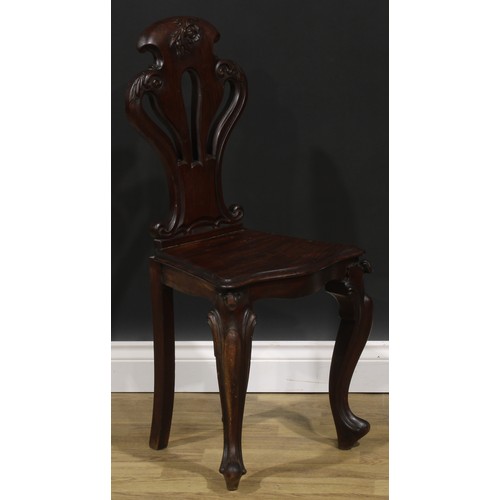 2535 - A pair of Victorian mahogany hall chairs, each with a pierced cartouche shaped back carved with a fl... 