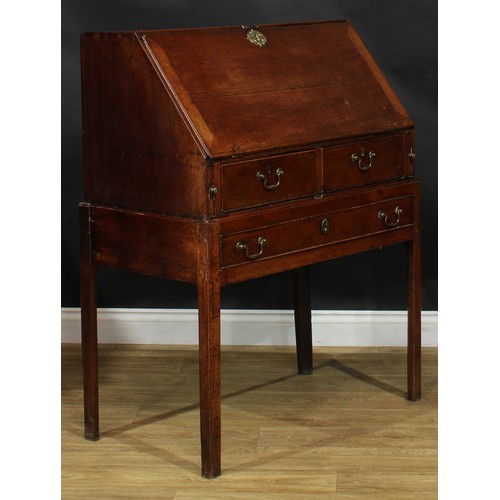 2041 - A George III vernacular oak bureau on stand, fall front enclosing small drawers and pigeonholes abov... 