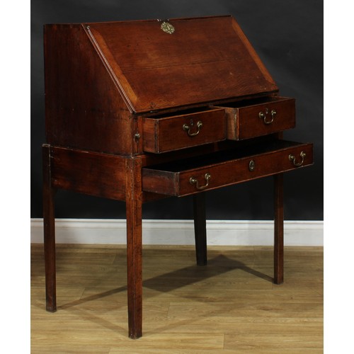 2041 - A George III vernacular oak bureau on stand, fall front enclosing small drawers and pigeonholes abov... 