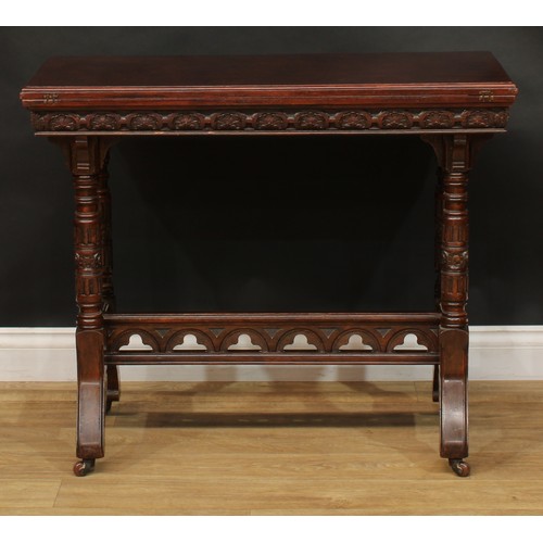 2592 - A Victorian Neo-Gothic oak card table, hinged top enclosing a baize lined playing surface above a de... 