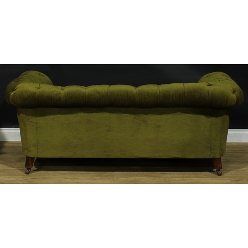 2256 - A Victorian Chesterfield sofa, stuffed-over deep-button upholstery, turned legs, ceramic casters, on... 