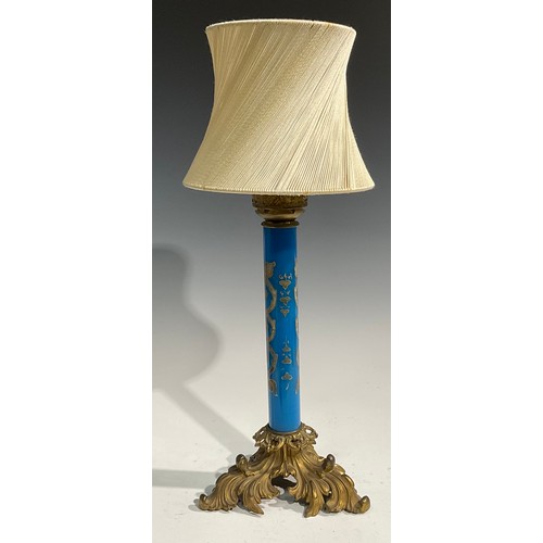 2667 - An early 20th century gilt metal and blue glass table lamp, the cylindrical pillar decorated in gilt... 