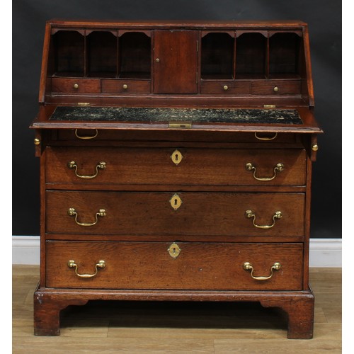 1941 - A George III oak bureau, fall front enclosing a small door, small drawers and pigeonholes, above fou... 