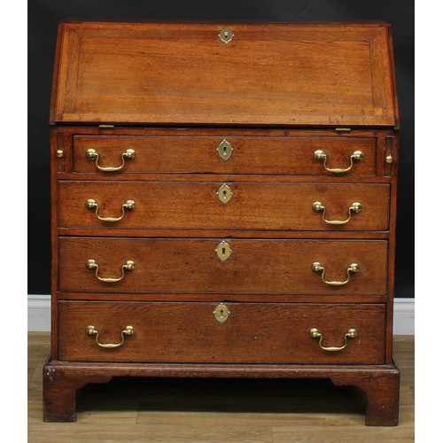 1941 - A George III oak bureau, fall front enclosing a small door, small drawers and pigeonholes, above fou... 