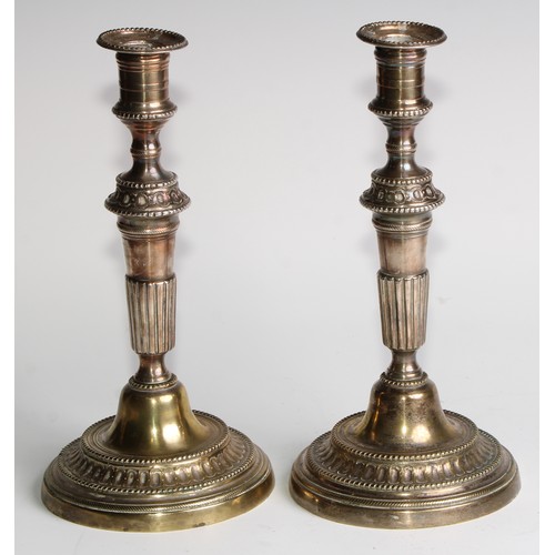 1809 - A pair of 18th century French brass table candlesticks, of seamed construction, tapered pillars, flu... 