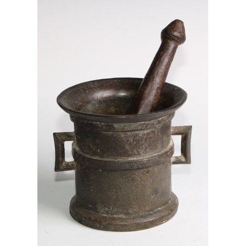 1679 - A cast iron pestle and mortar, flared rim above a quarter girdle, angular lug handles, skirted base,... 